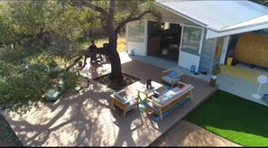 A deck with outdoor furniture, a covered patio area, and a house with a sliding glass door. - 6 bed resort Yurt at a luxury Austin Wellness  Ranch 10 minutes from downtown. (Austin)