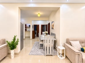 A modern living room with a dining area, a sofa, a potted plant, and a kitchen in the background. - Naguru Rise (Kampala)