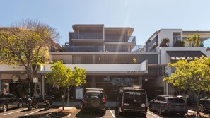 Een modern gebouw met een bordje met de tekst '36 DUKE STREET' en een parkeerplaats met verschillende voertuigen.