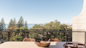 Een balkon met een tafel, stoelen en een schaal.