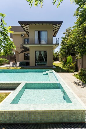Una casa moderna de dos pisos amb piscina, un balcó cobert i un jardí ben cuidat.