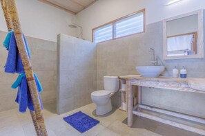 Et badeværelse med bruser, toilet og vask.