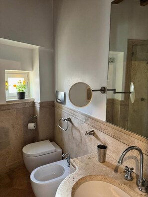 A bathroom with a toilet, bidet, sink, and a mirror. - Bramante Collection – Fico Apartment By RHR (ROMA)