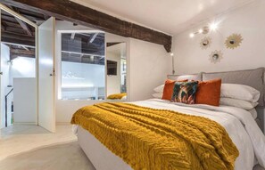 A bedroom with a bed, a window, and a door leading to another room. - Bramante Collection – Navona Apartment By RHR (ROMA)
