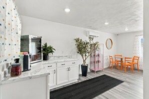 A modern kitchen with white cabinets, a marble countertop, and a dining area with orange chairs. - 915 W Main St (Branson)