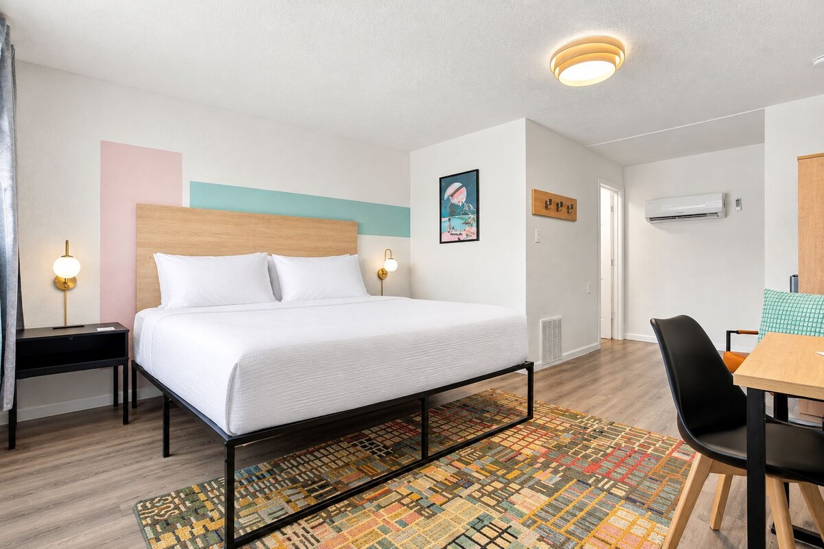 A hotel room with a bed, bedside tables, a desk, and a chair.
