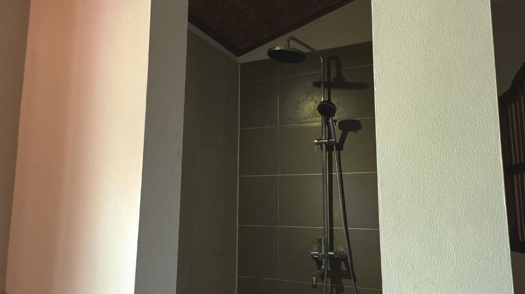 A shower area with a handheld showerhead and a wall-mounted faucet.