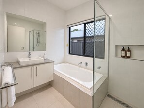 A modern bathroom with a glass-enclosed shower, a large bathtub, and a built-in sink. - The Slow Chapter｜A Park Ridge Retreat (Park Ridge)
