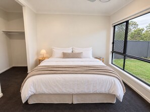 A bedroom with a large bed, a bedside table with a lamp, and a window with a view of the outdoors. - The Slow Chapter｜A Park Ridge Retreat (Park Ridge)