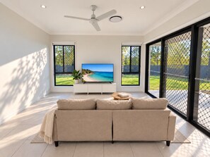 A modern living room with a flat-screen TV, a beige sofa, and a ceiling fan. - The Slow Chapter｜A Park Ridge Retreat (Park Ridge)