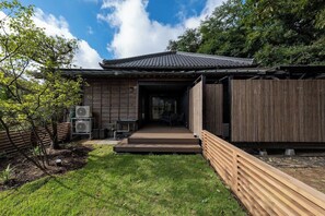 Een traditioneel Japans huis met een houten gevel, een pannendak en een klein terras.