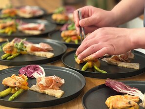 Iemand serveert eten op zwarte borden met diverse ingrediënten.
