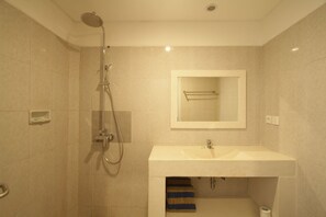 A bathroom with a shower, sink, and towel rack. - Mahamustika Riverside (Canggu)