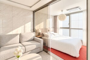 A modern hotel room with a bed, a sofa, a nightstand, a lamp, and a vase of flowers. - Hotel Comfort, Home Freedom _Studio Double_UH FLAT Seocho New Wing (Seoul)