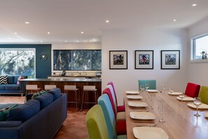 A modern living space with a dining area, kitchen, and seating. - The Blue Wren - Freycinet Holiday Houses (Coles Bay)