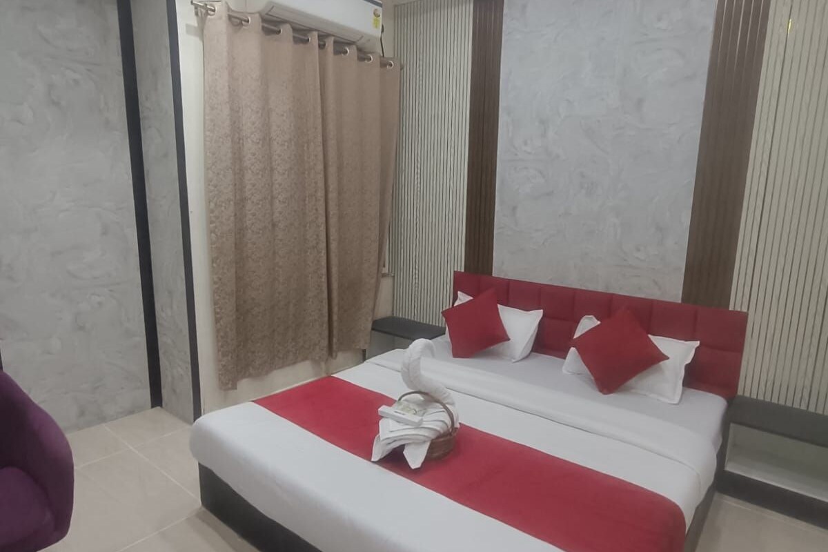 A hotel room with a bed, a chair, a small table, and a ceiling fan.