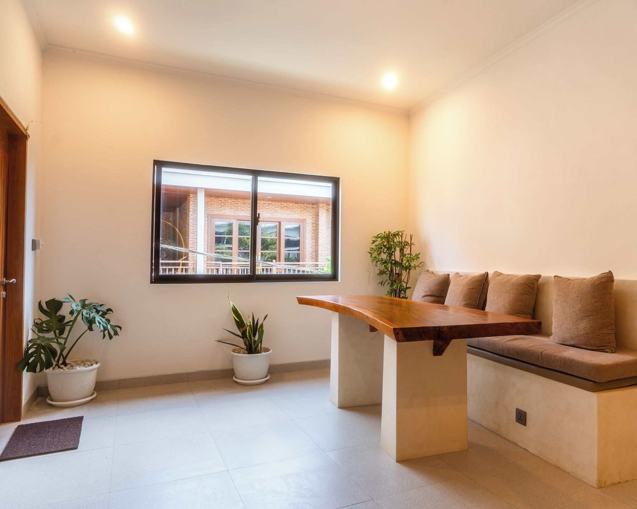 Una sala moderna con un sofá, una mesa de centro de madera y dos plantas en macetas.
