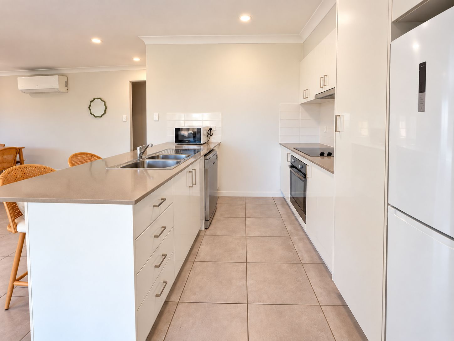 A modern kitchen with a central island, stainless steel appliances, and white cabinetry.