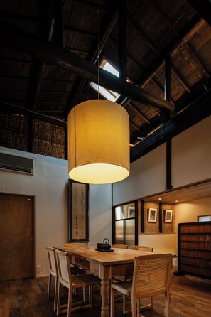 Un comedor con mesa de madera, sillas y una lámpara colgante.