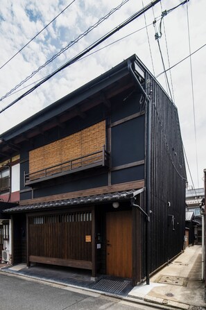 Un edificio japonés tradicional con fachada oscura, entrada de madera y tejado de tejas.