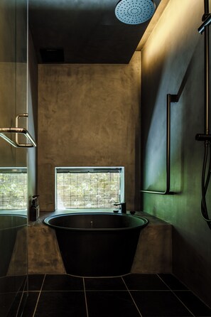 Un baño moderno con una bañera independiente, cabina de ducha con mampara de vidrio y una ventana con persianas.