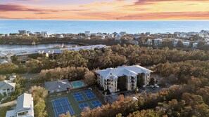 Un quartier résidentiel comprenant plusieurs maisons, un grand immeuble avec une piscine et des courts de tennis.