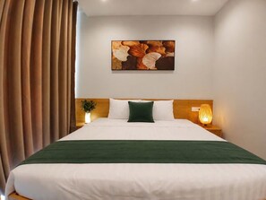 Een hotelkamer met een bed, nachtkastje, een lamp aan de muur en een schilderij.