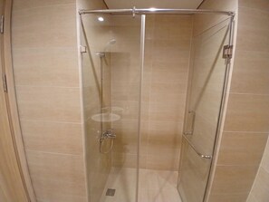 Een douchecabine met glazen wanden, een handdouche en een wandmengkraan.