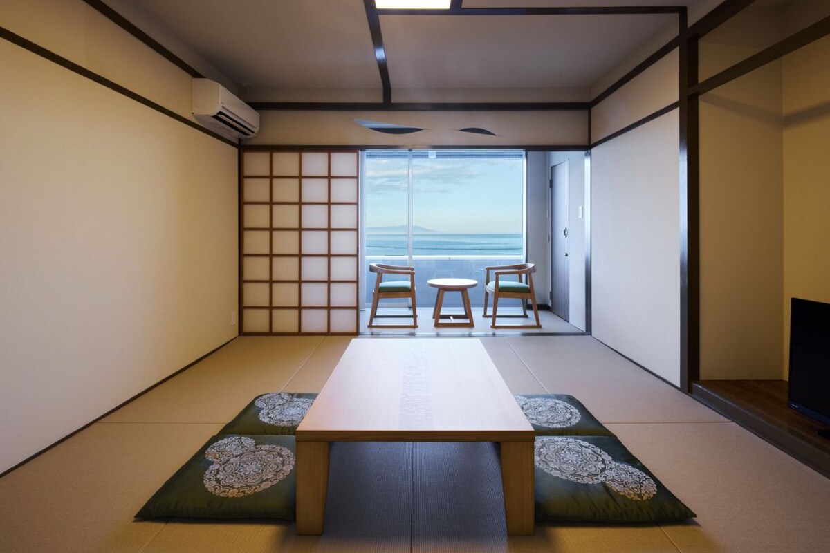 A traditional Japanese room with tatami flooring, a low table, and two chairs.