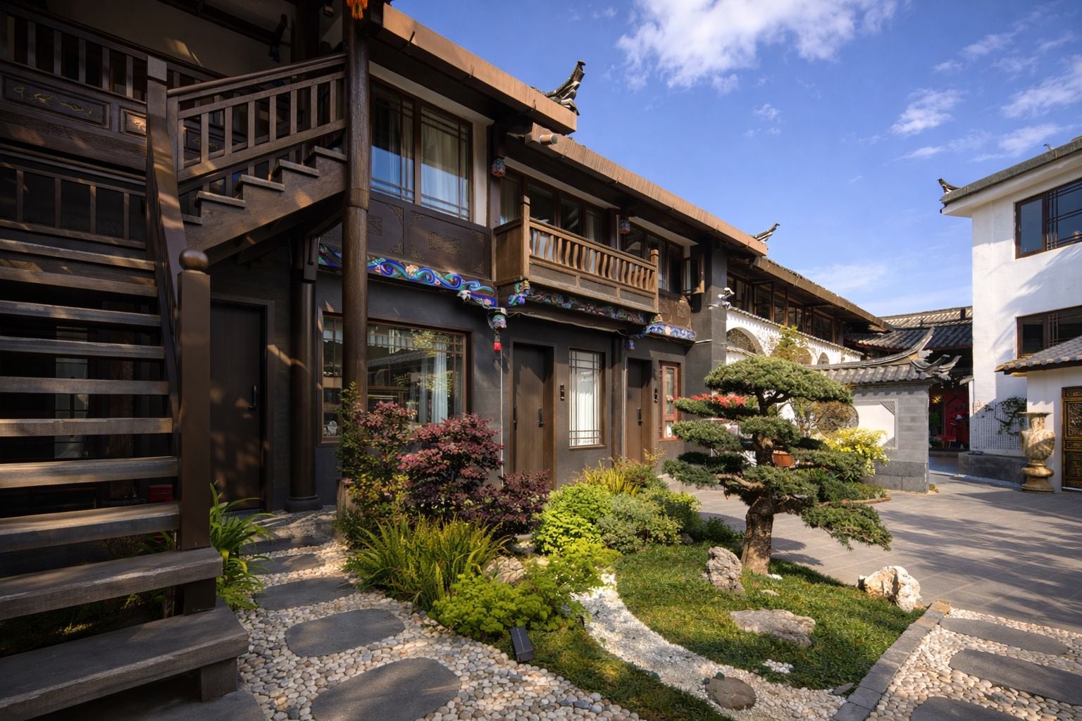 A traditional building with a wooden staircase, a balcony, and a garden with rocks and plants.