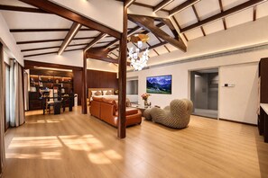 A spacious living area with a high ceiling, a fireplace, a seating area with a sofa and armchair, and a television mounted on the wall. - Lijiang Zhao's Mansion Resort (Mufu) (Lijiang)