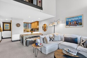 Ein modernes Wohnzimmer mit einem Ecksofa, einem Couchtisch und einem Essbereich mit Holzschränken.