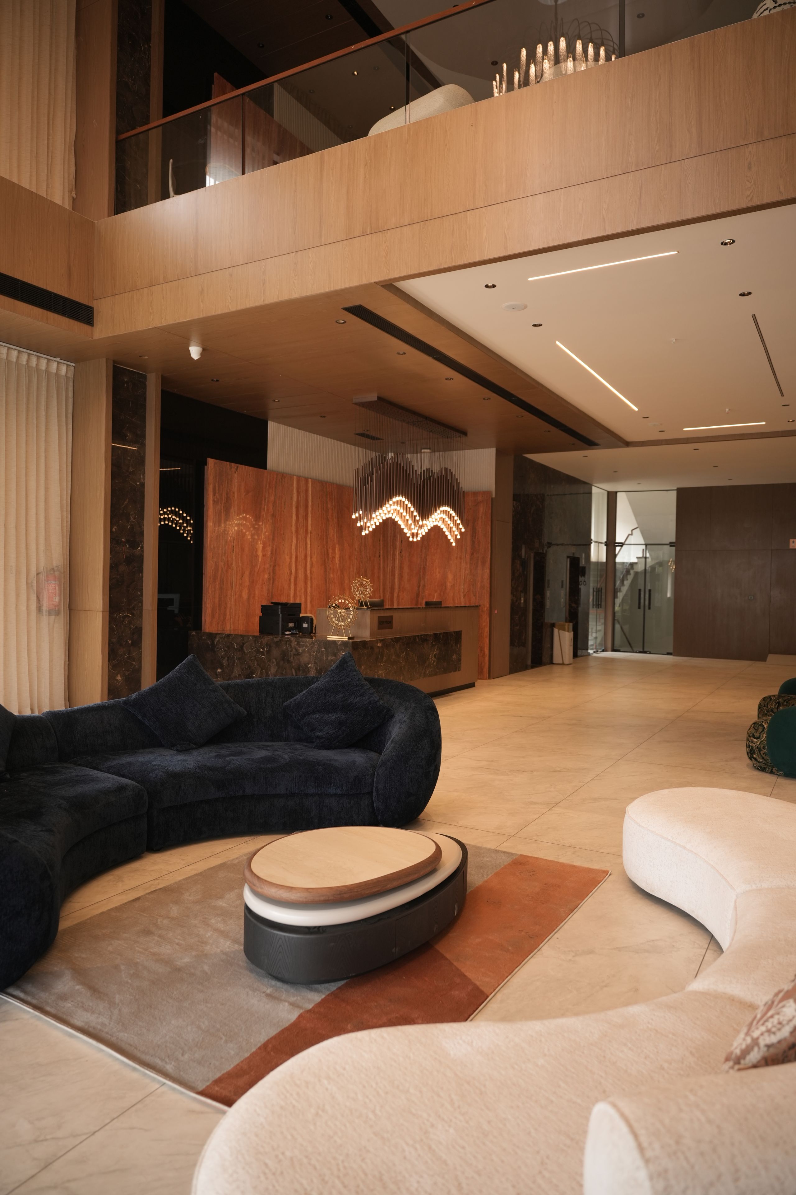 A modern interior with a sectional sofa, a round ottoman, and a reception desk.