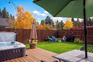 Een achtertuin met een jacuzzi, tuinmeubels en een houten terras.