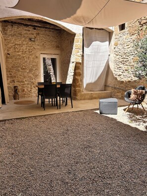 Ein Steinhaus mit einer überdachten Terrasse, komplett mit Tisch und Stühlen.