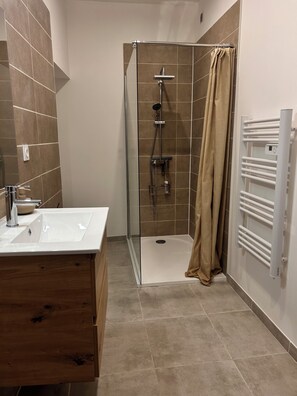 Ein modernes Badezimmer mit einer gläsernen Dusche, einem weißen Waschbecken und einem Handtuchhalter.