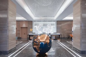 A lobby with a large globe sculpture, a world map projection on the wall, and a modern chandelier. - Kyriad Hotel (Shenzhen)