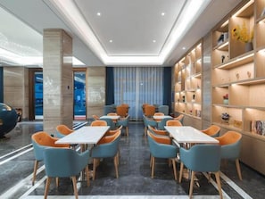 A modern hotel lobby with a central seating area, a bookshelf, and a marble floor. - Kyriad Hotel (Shenzhen)