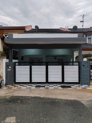 Une maison moderne dotée d’une entrée sécurisée par un portail, d’une antenne parabolique et d’un toit recouvert de tuiles.