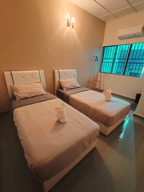 Une chambre d’hôtel avec deux lits, un luminaire fixé au mur, un appareil de climatisation et une fenêtre donnant sur un paysage agréable.