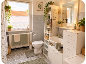 A bathroom with a toilet, sink, and shelves with toiletries. - Small and cozy room (Renchen)