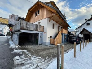 Een houten twee-onder-eenkapwoning met balkon, garage en een trap naar de bovenverdieping.