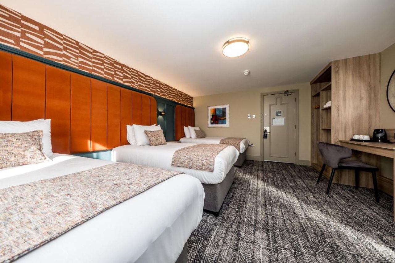 Una habitación de hotel con tres camas, un escritorio y una silla.