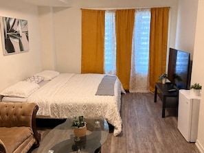 Une chambre d’hôtel avec un lit, une télévision, une petite table avec une plante et une chaise.