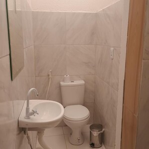 Pieni kylpyhuone, jossa on valkoinen pesuallas, wc ja roskakori.
