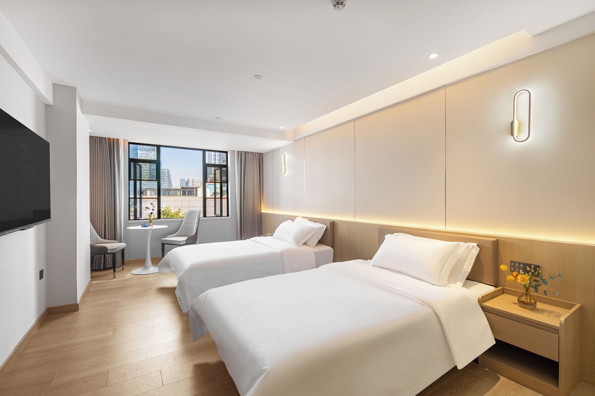 Une chambre d’hôtel avec deux lits, une télévision, un bureau et une vue sur la ville.