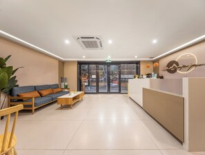 Un espace d’accueil moderne comprenant un canapé, une table basse et un comptoir de réception.