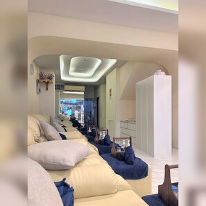A hotel room with a long sofa, a small table, and a mirror. - Arunvara Stay (Ratchathewi)