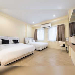 A hotel room with two beds, a desk, a chair, an air conditioning unit, and curtains. - Arunvara Stay (Ratchathewi)