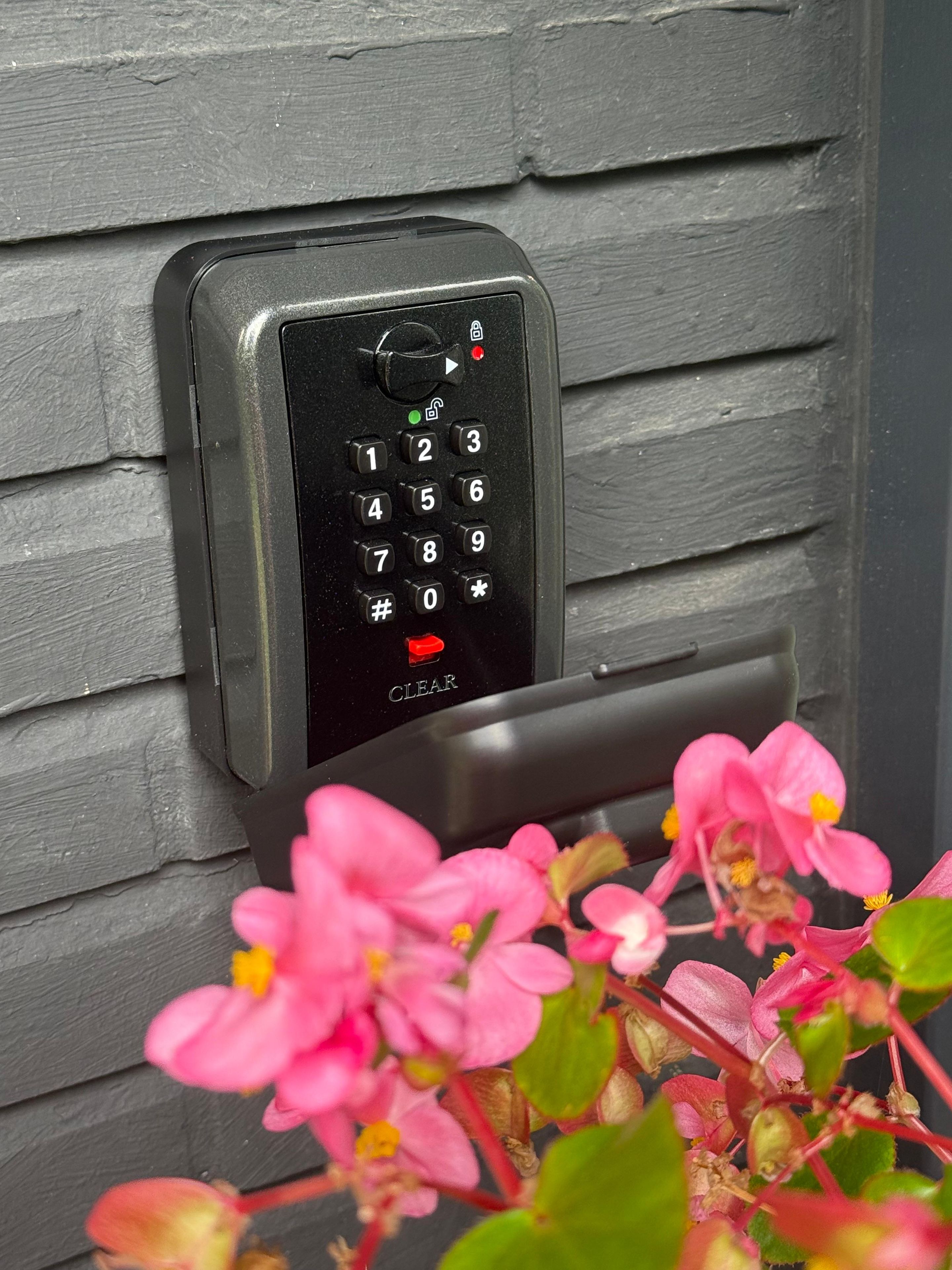 Un clavier à code est fixé sur un mur gris, avec un bouton transparent juste en dessous.